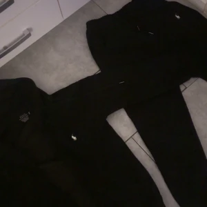 Svarta mjukisbyxor från Polo Ralph Lauren - Svarta mjukisbyxor från Polo Ralph Lauren med klassisk vit logga broderad på benet. Byxorna har dragsko i midjan och är gjorda i mjukt bomullsmaterial. Perfekta för chill eller häng med kompisar. Snygg och enkel design som alltid funkar. Passar i storlek M och S