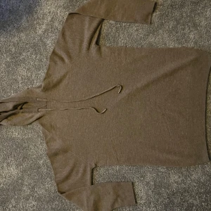 Beige hoodie i merinoull - Mjuk och lyxig beige hoodie i kashmir med huva och snörning. Tröjan har långärmad passform och ribbade muddar vid ärmslut och nederkant. Perfekt för dig som gillar en clean och chill stil med premiumkänsla.