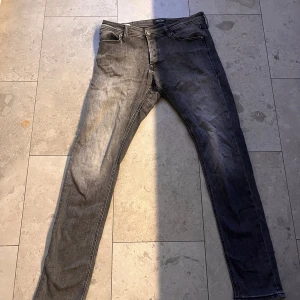 Slim Glenn jeans från Jack & Jones - Snygga svarta Slim Glenn jeans från Jack & Jones i storlek 33/32. Modellen har en slim passform med klassisk femficksdesign och dragkedja. Jeansen är tillverkade i mjukt denimtyg med lätt tvättad look och passar perfekt till en avslappnad stil.