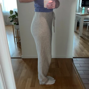 Beige mjukisbyxor från H&M med snörning - Supermysiga beige mjukisbyxor från H&M i storlek S. Byxorna har hög midja, bred resår och snörning i midjan för extra komfort. Materialet är mjukt och stickat, perfekt för dagar hemma. Passformen är loose och benen är raka. De har blivit något noppriga på insidan av benen men det går att få bort om man vill jag har bara inte orkat