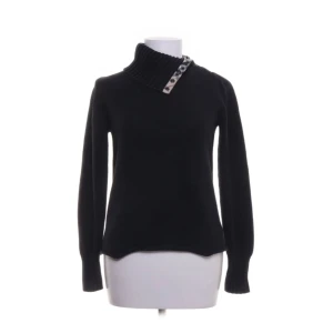 Svart polotröja Burberry London XS - Svart polotröja från Burberry London med ribbad hög krage och klassiskt rutigt tyg med knappar vid halsen. Tröjan är stickad i mjukt material och har långärmad passform. Snygg detalj med Burberrys ikoniska mönster på insidan av kragen. Storlek xs. Köpt på sellpy