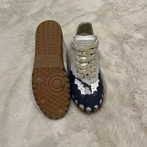 Maison Margiela sneakers med färgstänk - Helt nya maison margielas med färgstänk storlek 41, helt nya och ingår skolåda mm. Köpta här på Plick, Skriv för fler bilder och kan gå ner i pris vid snabb affär