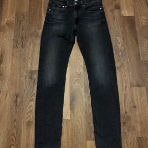 Svarta jeans från Calvin Klein, W31 L34 - Svarta jeans från Calvin Klein med klassisk femficksdesign och diskreta slitningar. Modellen har raka ben och normal passform, med snygga detaljer på bakfickorna. Perfekt för dig som gillar stilrena och tidlösa jeans.