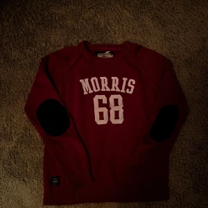 Stickad Morris tröja - Snygg mörkröd stickad tröja från Morris med vit text och siffran 68 framtill. Tröjan har svarta armbågslappar, ribbade muddar och rund hals. Tillverkad i 100% bomull. Hör av dig vid funderingar! Mvh Carl