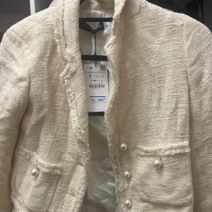Beige kavaj/jacka med pärlknappar från Zara - Helt ny med prislapp kvar, aldrig använd. Nypris: 899kr