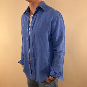 Blå linneskjorta Ralph Lauren - Nu säljer vi ännu en snygg polo skjorta som passar till alla tillställningar! Du ska kunna uttrycka stil utan att det kostar för mycket!🕺🍾💼🤩  Storlek👔: S Nypris💰: ca 1399kr