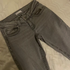 Grå bootcut jeans  - Grå bootcut jeans från Perfect Jeans i klassisk y2k-stil. Jeansen har låg midja, fem fickor och coola sömdetaljer. Tillverkade i mjukt denim-material som sitter skönt och ger en avslappnad vibe. 