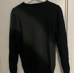 Svart tröja från Stone Island - Svart långärmad tröja från Stone Island med klassisk rund hals och ikonisk logopatch på bröstet. Tröjan har en enkel och clean design, perfekt för dig som gillar streetwear och vill ha något stilrent. Materialet känns mjukt och bekvämt mot huden.