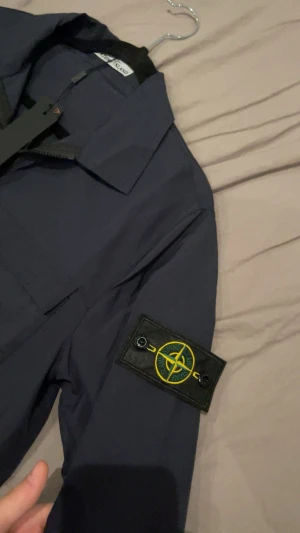Mörkblå overshirt från Stone Island - Säljer en stilren overshirt från Stone Island. Modellen har dragkedja framtill, klassisk krage och två praktiska bröstfickor som ger både funktion och ett clean uttryck. Perfekt som lätt jacka eller lager på lager – en mångsidig och tidlös del i garderoben. Perfekt för hösten! 🙌🫡