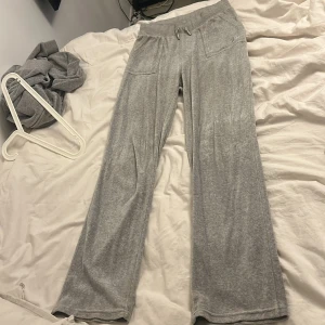Grå mjukisbyxor med hoodie till - Säljer ett par grå mjukisbyxor med bred resår och snörning i midjan. Byxorna har raka ben, två stora fickor fram och två fickor bak med knappdetalj. Materialet är mjukt och skönt, perfekt för chill dagar. Storlek M på tröja storlek S på byxor. 