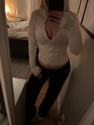 Vit zip hoodie  - Säljer en vit zip hoodie med långa ärmar och tumhål. Tröjan har en åtsittande passform och dragkedja framtill. Perfekt för en avslappnad och sportig stil. Materialet är mjukt och stretchigt, kommer från Gina Tricots Soft Tutch kollektion. 