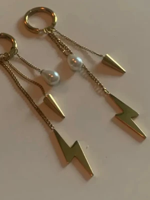 Peak Hoops Multi - Hängande örhängen - Edblad  örhängen i guldplaterad 14 stål  metall med hängande detaljer som vita pärlor, konformade hängen och blixtar. Kedjorna ger ett coolt och trendigt uttryck. Perfekta för att lyfta din stil med en unik touch. 14 k 