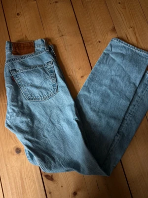 Levi's ljusblå raka jeans - Säljer ett par klassiska ljusblå jeans från Levi's med rak passform och hög midja. Jeansen har fem fickor, tydlig läderpatch bak och den ikoniska röda Levi's-taggen på bakfickan. Perfekta för en avslappnad och trendig look.size W 26 L 30