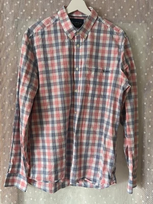 Rutig skjorta från Bondelid - Säljer en klassisk rutig skjorta från Bondelid i ljusblått, rosa/rött och vitt. Skjortan har lång ärm, knappar framtill och en bröstficka med broderad logga. Tillverkad i mjuk bomull, perfekt för en avslappnad men snygg look. Storlek L - Tailored Fit. Rök och Djurfritt hem!