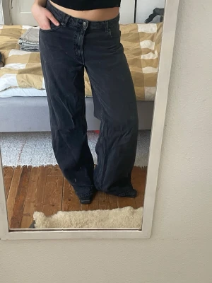 Svarta wide leg jeans - Säljer ett par svarta jeans från pull & bear med wide leg-passform och hög midja. Jeansen har klassisk femficksdesign och stängs med knapp och dragkedja. Perfekta för en avslappnad och trendig stil.