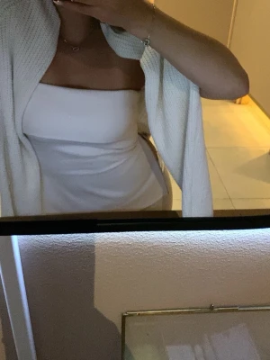 Vit axelbandslös topp från Zara - Säljer en stilren vit axelbandslös topp från Zara i storlek S. Toppen har en snygg draperad framsida och dragkedja på båda sidorna, går även att dra upp eller ned dem om man vill.  Perfekt till sommaren passar till både jeans och kjol.