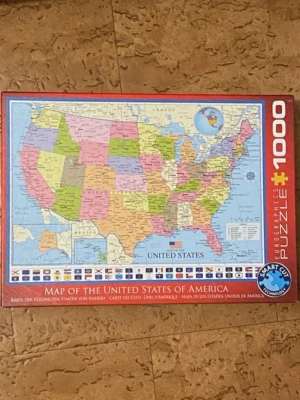 Pussel USA-karta 1000 bitar - Säljer ett pussel med 1000 bitar från Eurographics som visar en färgglad karta över USA. Perfekt för dig som gillar geografi och utmanande pussel. Kartan har tydliga delstatsgränser och flaggor längst ner. Pusslet har röd ram och Smart Cut-teknologi.