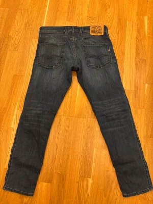 Mörkblå jeans från Replay med unik färg/mönster - Säljer ett par mörkblå jeans från Replay med unik design och raka ben. Jeansen har snygga slitningar och detaljerad söm på bakfickorna. Tillverkade i bomull med en liten mängd stretch för extra komfort. Slim fit. 