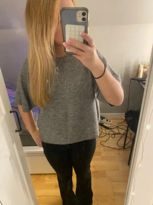 Grå stickad tröja med kort ärm - Mysig grå stickad tröja med avslappnad passform och korta ärmar. Perfekt för lager-på-lager och chill dagar. Enkel design utan mönster eller detaljer, passar dig som gillar basic och comfy vibes.