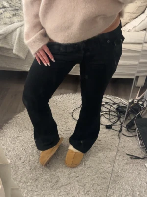 Svarta bootcut true religion jeans - Säljer ett par svarta bootcut jeans från true religion med klassisk femficksmodell och låg midja. Jeansen har en snygg utsvängd passform och är tillverkade i ett mjukt denimtyg som sitter bekvämt. Perfekta för dig som gillar en tidlös och trendig look.