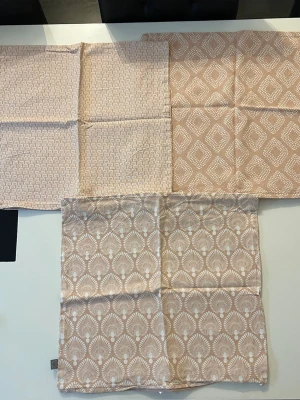 3-pack beiga kuddfodral med mönster från Jotex - Tre kuddfodral i beige och vitt med olika grafiska mönster från Jotex. Tillverkade i 100% bomull. Storleken på kuddfodralen är 45x45.