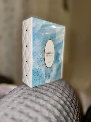 Ny Victoria parfym från Lattafa - Snygg parfym från Lattafa i en elegant blå och vit förpackning med quiltad struktur på sidorna och gulddetaljer runt etiketten. Doften heter Victoria och boxen har ett modernt, lyxigt utseende som sticker ut i badrumshyllan.