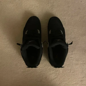 Svarta Jordan 4 Skor - Säljer ett par svarta Jordan 4 sneakers med grå och vita detaljer. Hör av er vid frågor.