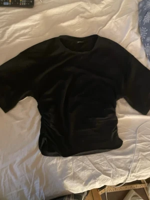 Svart topp från gina tricot - Snygg svart tröja som sitter tightare vid magen och har lösare armar, använd fåtalgånger och har en väldigt fin passform som passar alla olika kroppar, skriv privat för bilder på