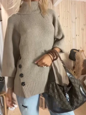 Beige stickad polotröja med knappar - Säljer en beige stickad polotröja med stora svarta knappar längs sidan. Tröjan har en hög polokrage, avslappnad passform och trekvartsärmar. Perfekt för lager på lager och riktigt mysig till hösten.