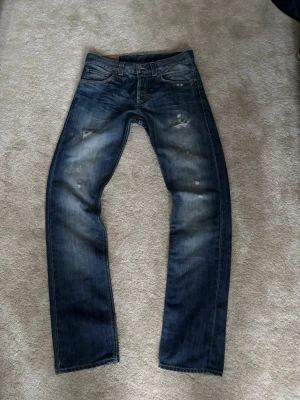 Blå dondup jeans med slitningar - Säljer ett par blå dondup jeans med populära slitna detaljer på framsidan. Jeansen har klassisk femficksdesign och en tvättad look med bra färger. Perfekta för en avslappnad, trendig och laidback stil. Ny pris ca 3000. Mitt pris 749!. Pris kan diskuteras!