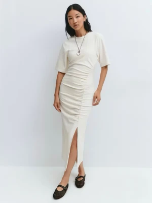 Krämvit långklänning från Gina Tricot - Supersnygg krämvit långklänning från Gina Tricot med korta ärmar och rynkade detaljer längs ena sidan. Klänningen har en enkel, stilren design och är tillverkad i mjukt bomullsmaterial, klänningen har en snygg slits som man ser på bilderna. Perfekt för dig som gillar minimalistisk stil.✨🌸