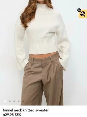 Vit stickad tröja med funnel neck - Trendig vit stickad tröja med hög funnel neck och vida ärmar. Croppad modell med bred ribbstickad kant nedtill och vid halsen. Perfekt att styla med höga byxor för en clean look.