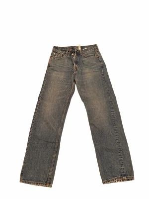 Blå raka jeans från weekday  - Klassiska blå jeans från weekday med rak passform och fem fickor. Jeansen har en vintage tvätt och är tillverkade i slitstark denim. Perfekta för dig som gillar en tidlös och avslappnad stil.