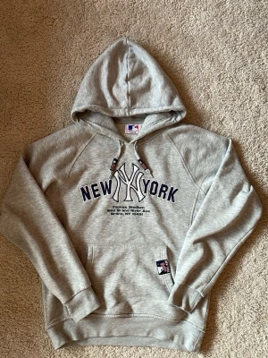 Grå New York Yankees hoodie - Snygg grå hoodie från New Era med stor New York Yankees-logga. Sällsynt och riktigt chill. Tröjan är märkt som storlek 164 men enligt mig passar den xs mycket bättre 