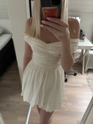 Vit offshoulder klänning - Söt vit kortklänning med offshoulder-design och rynkade detaljer över bysten. Aldrig använd då jag hitta annan studentklänning. Perfekt för studenten och sommaren!💕