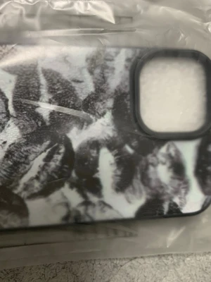 Mobilskal med svartvita läppavtryck - Snyggt mobilskal med svartvita läppavtrycksmotiv. Skalets yta är lätt texturerad och har en rektangulär öppning för kameran. Passar dig som vill ha ett unikt och trendigt skydd till mobilen. Materialet känns som tålig plast. Helt ny!! Aldrig använd! Köpt fel 😑 