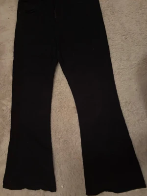 Svarta bootcut jeans - Säljer ett par svarta bootcut jeans med utsvängda ben. Klassisk femficksmodell och hög midja. Perfekta för dig som gillar en tidlös och trendig look. Passar till sneakers eller boots.
