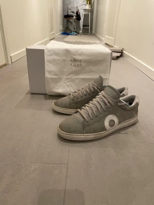 Gråa Oliver Cabell  - Snygga gråa sneakers från Oliver Cabell i skinn med vita detaljer och rund logotyp på sidan. Skorna har vita sulor och matchande grå skosnören. Perfekta för dig som gillar stilrena och minimalistiska sneakers med premiumkänsla. Skorna är i bra skick men har tecken på andvändning. Skorna är köpta nya så det är bara att fråga vid minsta fundering!🤩