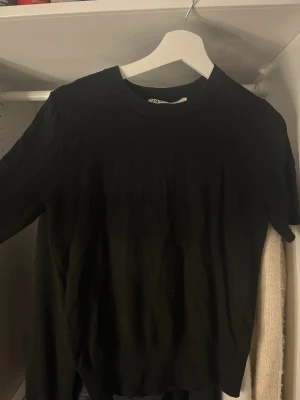 Svart topp från Zara - En enkel svart topp från Zara med rund halsringning och korta ärmar. Perfekt basplagg att matcha med olika outfits. Tunn och mjuk i materialet, passar året runt.