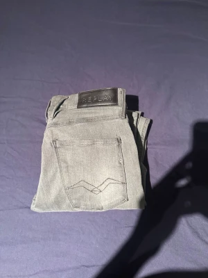 Gråa Replay jeans med smal passform - Snygga gråa jeans från Replay med smal passform och klassisk femficksdesign. Jeansen har en diskret tvättad look och svart Replay-lapp bak i midjan. Perfekta till en avslappnad stil och tillverkade i mjukt denimtyg.