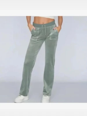 juicy couture gröna byxor - Snygga gröna mjukisbyxor i mjuk velour med raka ben och bred resår i midjan. Byxorna har dragsko och två fickor fram. Perfekta för en chill och avslappnad stil.