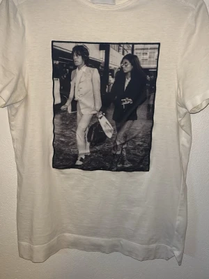 Vit t-shirt med print från Limitato - Vit t-shirt från Limitato med ett stort svartvitt fotoprint på framsidan. Klassisk rund halsringning och korta ärmar. T-shirten har en stilren och modern vibe, perfekt för dig som gillar unika motiv och streetstyle.