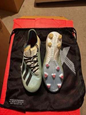 Adidas X 19.1 blå fotbollsskor, stl 41 1/3 - Säljer ett par Adidas X 19.1 fotbollsskor med snyggt randigt mönster i ljusblått och beige. Ovandelen är tillverkad i syntetmaterial för lätt vikt och bra passform. Storlek 41 1/3. Använda men i bra skick. Priset är aningen förhandlingsbart. 