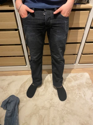 Diesel mörkblå/gråa jeans straight fit - Säljer ett par mörkblå jeans från Diesel med klassisk straight fit och snygga detaljer på bakfickorna. Jeansen har knappgylf och kontrastsömmar. Regält omsydda i skrevet men professionellt av min mormor 👵 