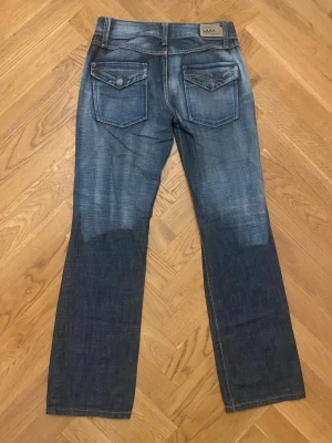 Lågmidjade utsvängda jeans - Lågmidjade jeans med snygga detaljer i storlek 36. Jag är 167cm lång och längden är bra på mig. 