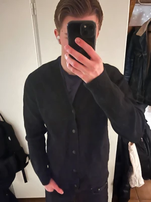 Svart kofta perfekt till vintern - Svart i storlek M. Klassisk design med v-ringning och knappar framtill. Mjuk stickad känsla och långa ärmar, perfekt för lager-på-lager. Passar dig som gillar enkel och clean stil. Perfekt nu till vintern