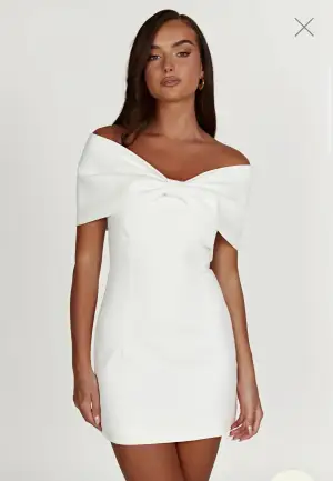 Vit off-shoulder klänning med figurnära passform och rosettdetalj framtill. Perfekt till student, fest eller bröllop.                                                         Endast provad!                                                    Säljes då den var för liten och ej går att returnera. Nypris 1700kr. (pris går att diskutera🫶🏻)