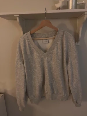 Grå v-ringad sweatshirt från Bershka - Grå sweatshirt från Bershka med v-ringad hals och avslappnad passform. Tröjan har långa ärmar och ribbade muddar vid ärmslut och nederkant. Perfekt för chill dagar och enkel att matcha med jeans eller mjukisbyxor. Skriv för fler bilder/funderingar❤️❤️