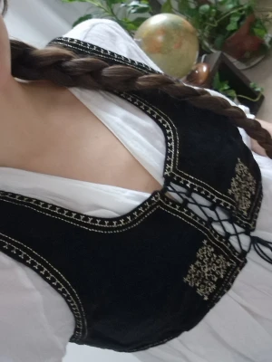 Velvet vest with embroidery - Cropped velvet vest (blouse bodice) with inspiration from the Balkans. Brand: Voriagh (model: Nelda). The string is intact, so I would assume it fits from S-L, depending on your bust size and width. The body is 82 cm around measured bust-back-bust and 31 cm long. With the straps it can be even broader around. New price approx. 950:-. No signs of use 