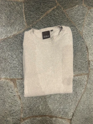 Beige kashmirtröja Oscar Jacobson  - Snygg beige rundhalsad tröja från Oscar Jacobson i lyxig kashmir och ull blandning. Tröjan har ribbade muddar vid ärmslut och nederkant samt klassisk passform. Perfekt för dig som gillar stilrena och mjuka plagg. Nypris: 1499. Notera att jag har råkat tvätta den i för hög grad vilket har krympt den. Därför är tröjan i storlek S-M 